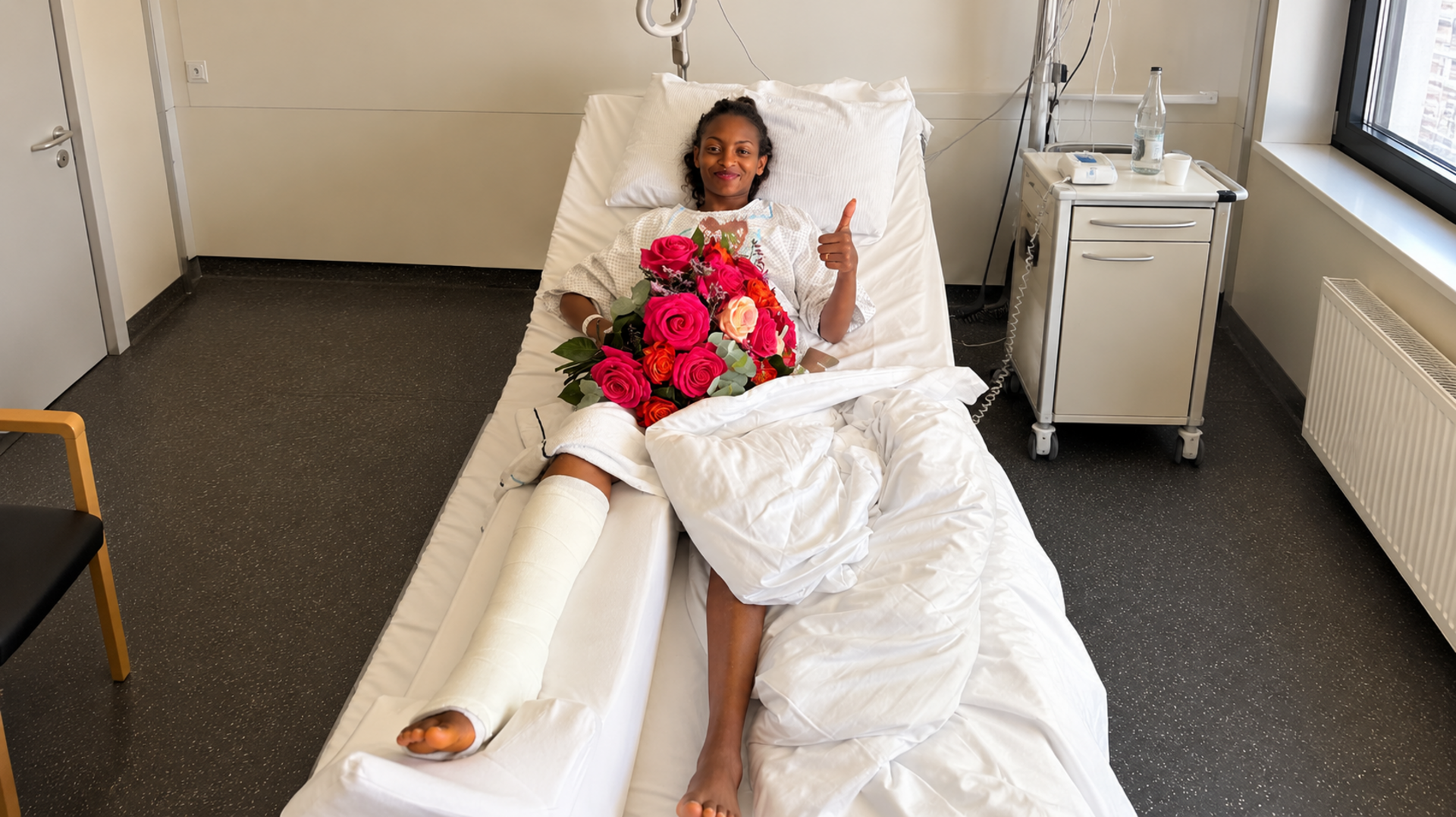 Tigst Assefa liegt im Krankenbett und zeigt den Daumen hoch.