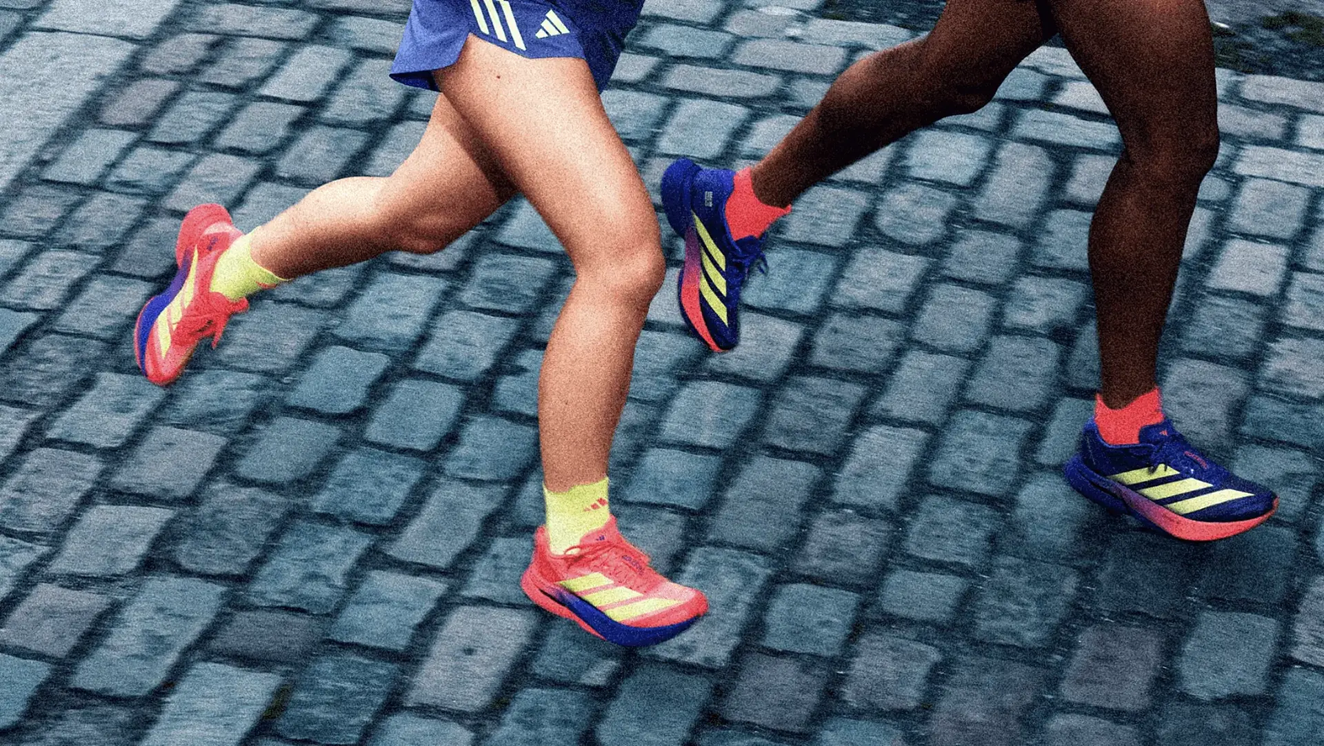 Two runners wearing different shoes from the adidas Marathon collection are running on cobblestones. Only their legs are visible.